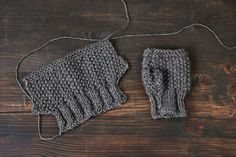 a pair of knitted gloves sitting on top of a wooden table