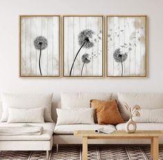 two paintings hanging on the wall above a couch in a living room with white furniture