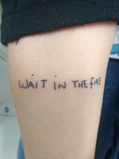 a woman's arm with the words wait in the fire written on her left side