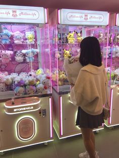 a woman is looking at stuffed animals in a toy store display case with neon lights