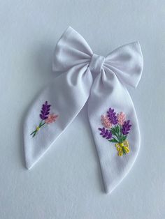 two white bows with flowers on them are sitting next to each other and one has a bow at the top