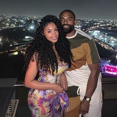 a man and woman standing next to each other in front of a cityscape