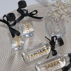 three personalized glass bottles with black ribbon tied around them