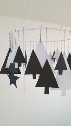 several paper christmas trees hanging from a circular white chandelier with black and white shapes