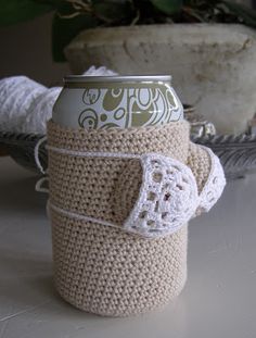 a crocheted can holder with a beer in it on top of a table