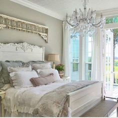 a white bed sitting in a bedroom next to a large glass sliding door and a chandelier