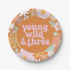 an orange plate with the words young wild and three on it, surrounded by flowers