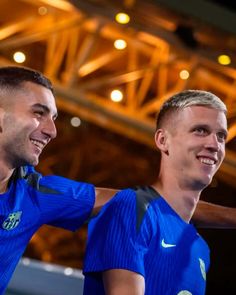 two men in blue soccer uniforms standing next to each other with their arms around one another