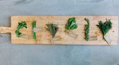 a wooden cutting board topped with lots of green vegetables