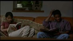 two people sitting on a couch reading books