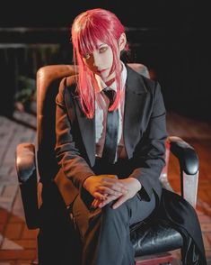 a woman with pink hair sitting in a chair