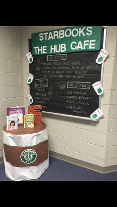 a starbucks coffee shop has a sign on the wall that says starbucks, and there is a table with books in front of it