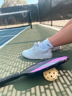 a person sitting on a tennis court next to a racquet