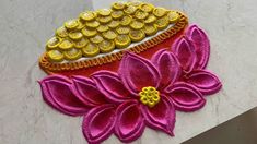 two flowers made out of gold coins on a white table top with pink and yellow petals