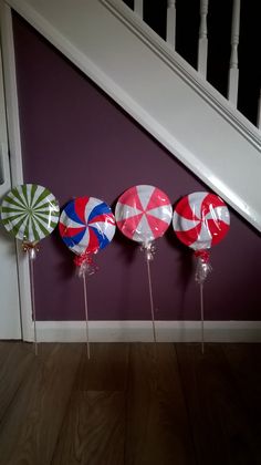 four lollipops are lined up on the floor in front of a stair case