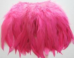 a pink feathered object on a white surface with one piece cut off and the other half closed