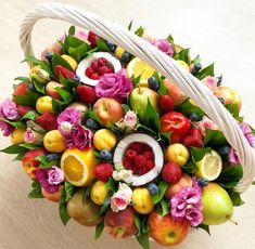 a basket filled with fruit and flowers on top of a table