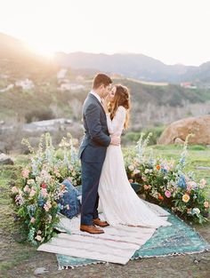 a bride and groom standing in front of an outdoor ceremony arch with flowers on it