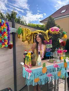 a woman standing behind a table with pineapples on it and balloons in the air