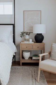 a bedroom with a bed, nightstand and chair next to a lamp on a table