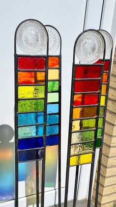 two stained glass windows sitting next to each other on top of a sidewalk near a building