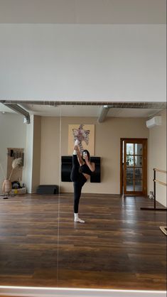 a woman standing on top of a wooden floor in front of a mirror holding onto a string