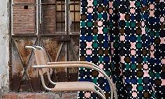 a chair sitting in front of a window next to a curtain with geometric designs on it