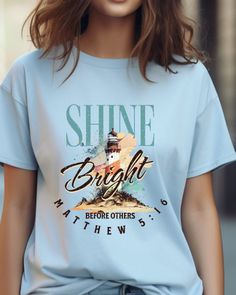 Embrace the radiant message of our 'Shine Bright Before Others' tee, inspired by Matthew 5:16. This uniquely designed shirt features a captivating lighthouse motif, symbolizing guidance and illumination. The distressed look adds a touch of vintage charm, reflecting the timeless wisdom of the scripture. Let your light shine in style with this comfortable and meaningful tee, available in six sizes for the perfect fit. Share the message of positivity and light wherever you go, and be a beacon of inspiration to those around you. Wear your faith proudly with this one-of-a-kind shirt that combines style, scripture, and a touch of vintage flair.  The unisex soft-style t-shirt puts a new spin on casual comfort. Made from very soft materials, this tee is 100% cotton for solid colors. Heather colors Christian Tee Shirts, Matthew 5, Bible Verse Shirt, Let Your Light Shine, Christian Tees, Christian T Shirt, Light House, Soft Style, Shine Bright