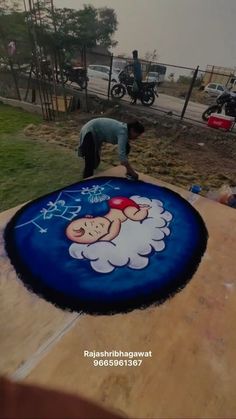 a man is working on a large painting in the ground with his feet propped up