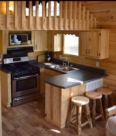 a kitchen with an oven, stove and stools next to the counter top in wood paneling