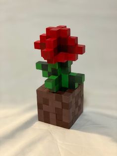 a red flower sitting on top of a blocky planter made out of legos