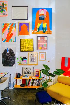 a living room filled with lots of art on the wall above a yellow couch and chair