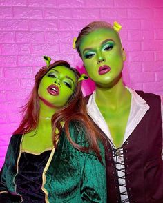 two people dressed in green and purple posing for the camera