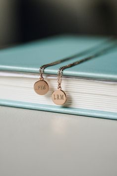 two personalized necklaces sitting on top of a book with the word i am written on it