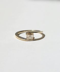 an engagement ring with a square cut diamond in the center on a white table top