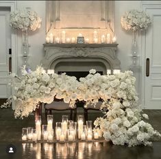 white flowers and candles are arranged in front of a fireplace for a formal wedding ceremony