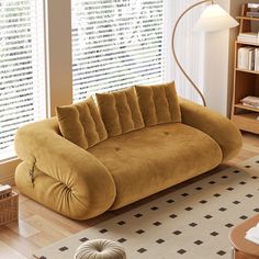 a brown couch sitting on top of a hard wood floor next to a book shelf