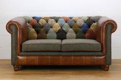 a brown leather couch sitting on top of a hard wood floor next to a white wall