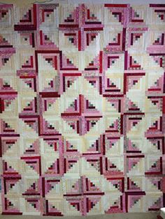 a pink and white quilt hanging on the wall