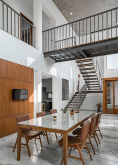 a dining room table with chairs and a staircase in the back ground, next to an open floor plan