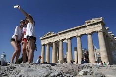 two women standing on top of a rocky hill next to an old building with columns