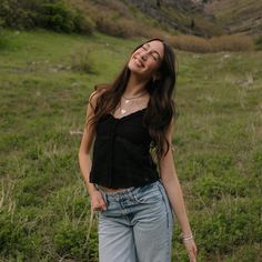 a young woman standing in a field with her eyes closed and one hand on her hip