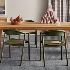 a wooden table topped with green chairs next to a painting on the wall in a living room