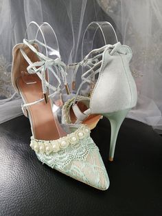 a pair of white shoes with pearls on the toes and heels are sitting on a black surface