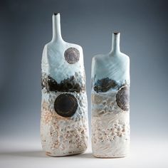 two ceramic vases sitting next to each other on a table