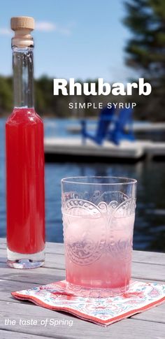 a bottle of rhubarb sitting next to a glass on a wooden table