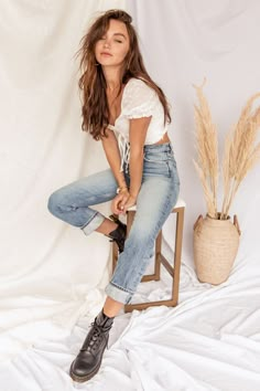 a woman sitting on top of a wooden chair next to a potted grass plant