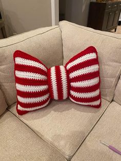 a red and white crocheted bow pillow on a couch