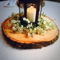 a candle that is sitting on top of a piece of wood with flowers around it