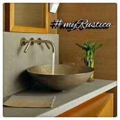 a bathroom sink sitting under a mirror next to a wooden cabinet and counter top with a plant in it